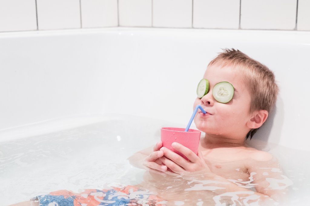 young-happy-boy-having-a-calming-bath-in-a-hot-tub-drinking-juice.jpg